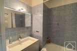 This bathroom features a modern design with blue tiled walls and a sleek white vanity.