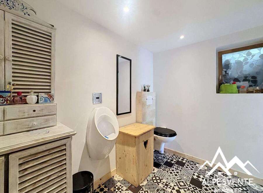 Discover this charming bathroom featuring a unique design with a urinal and a toilet.