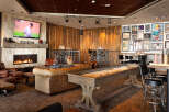 This cozy lounge features a warm fireplace, comfortable seating, and a shuffleboard table, perfect for relaxing and socializing.