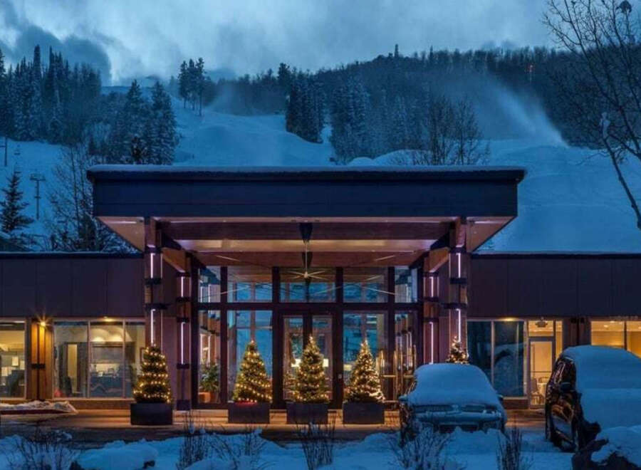 Experience the ultimate winter getaway at this stunning property! Featuring a grand entrance, the building is surrounded by snow-covered landscapes, and decorated with Christmas trees.