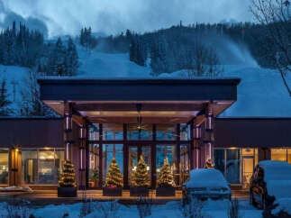 Experience the ultimate winter getaway at this stunning property! Featuring a grand entrance, the building is surrounded by snow-covered landscapes, and decorated with Christmas trees.