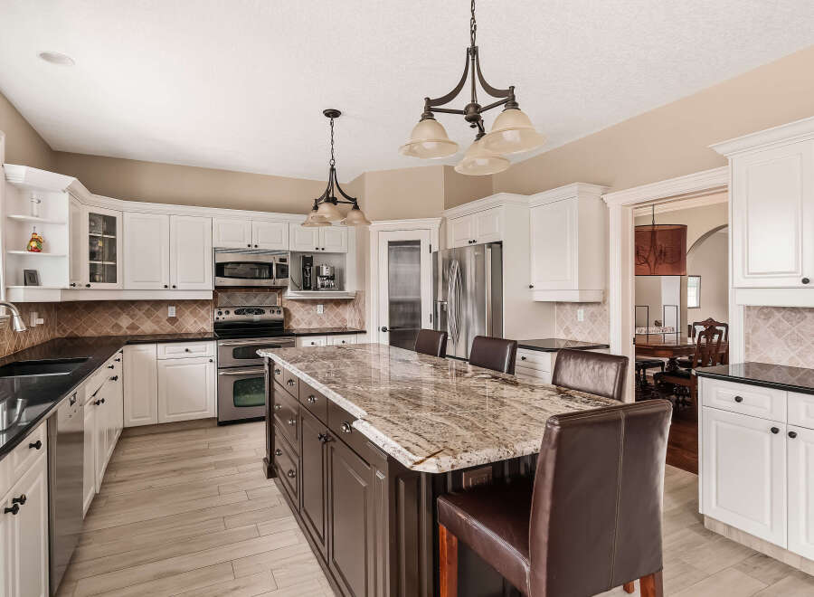 This stunning kitchen boasts a spacious island with a beautiful granite countertop, perfect for meal prep and casual dining.