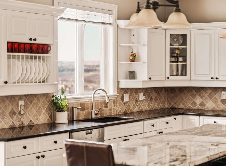 This stunning kitchen boasts elegant white cabinetry, a sleek black countertop, and a beautiful backsplash.