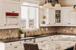 This stunning kitchen boasts elegant white cabinetry, a sleek black countertop, and a beautiful backsplash.