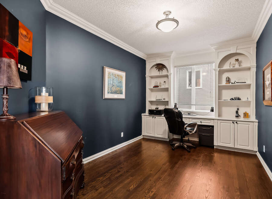 This stunning home office boasts a sophisticated design with dark blue walls and rich hardwood floors.