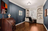 This stunning home office boasts a sophisticated design with dark blue walls and rich hardwood floors.