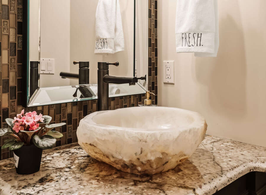 This stunning bathroom features a unique stone sink and a modern faucet, creating a luxurious and inviting space.
