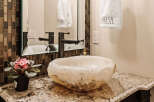 This stunning bathroom features a unique stone sink and a modern faucet, creating a luxurious and inviting space.