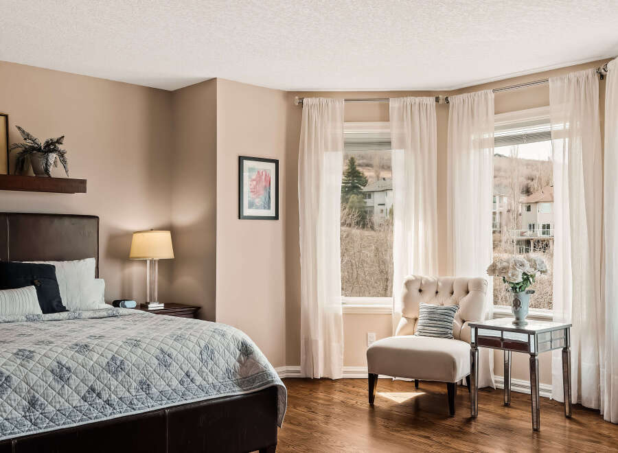 This elegant bedroom offers a serene retreat with its neutral color palette and abundant natural light.
