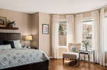 This elegant bedroom offers a serene retreat with its neutral color palette and abundant natural light.