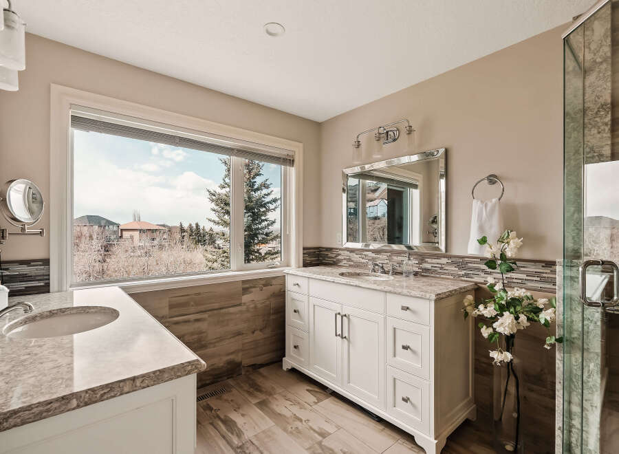 Step into luxury with this stunning bathroom featuring a spacious vanity and a large window offering breathtaking views.