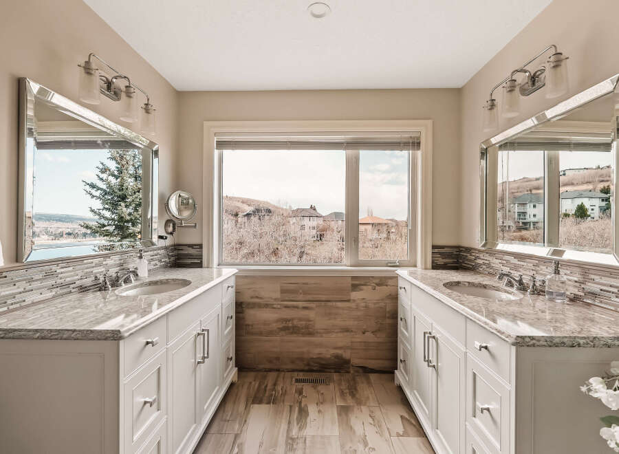 This stunning bathroom features dual vanities with elegant marble countertops and ample storage.