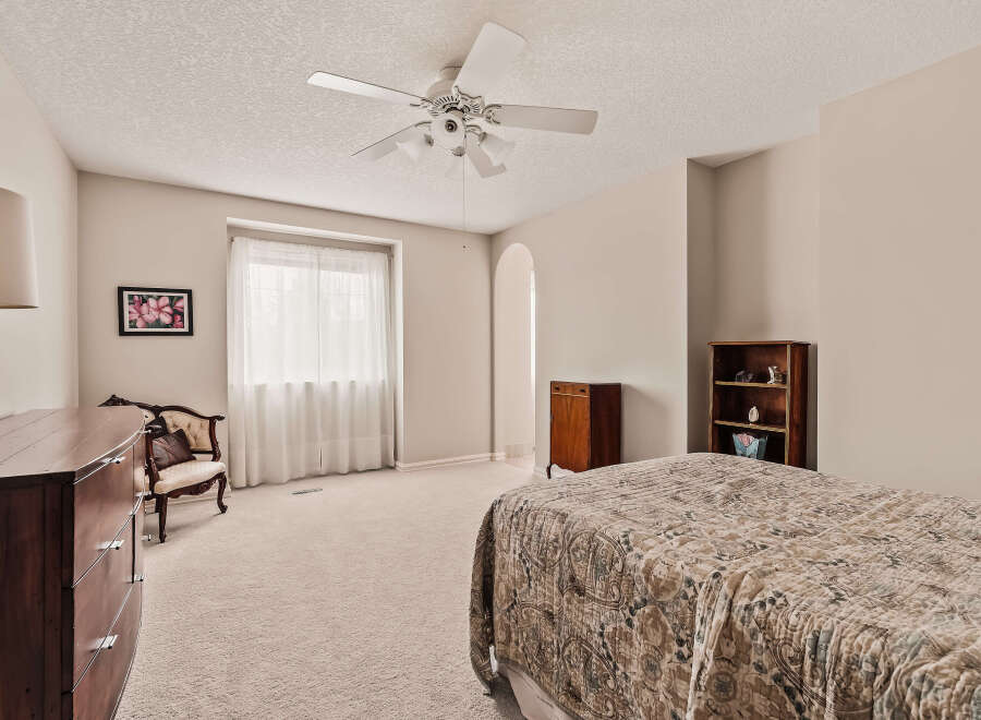 This spacious bedroom offers a serene retreat with its neutral color palette and ample natural light.