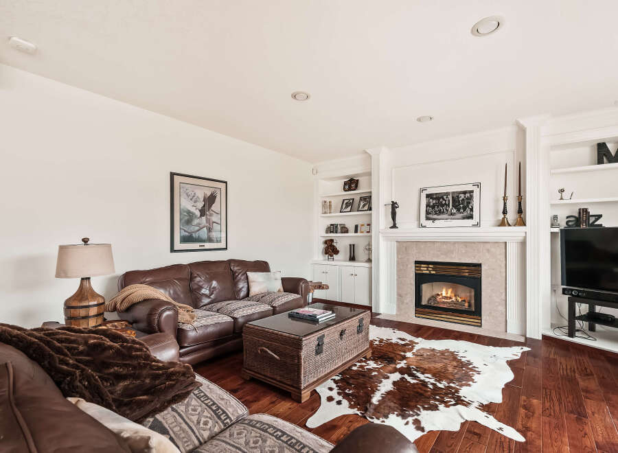 This stunning living room boasts a cozy fireplace, perfect for chilly evenings, and a beautiful cowhide rug adding a touch of rustic elegance.