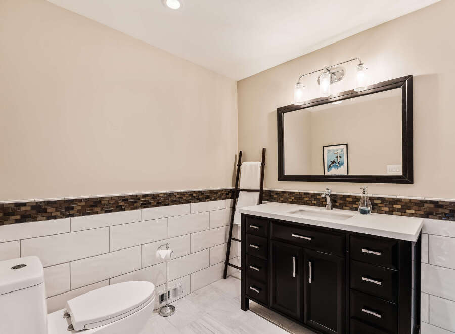 This stunning bathroom features a modern design with a dark wood vanity and a sleek white countertop.