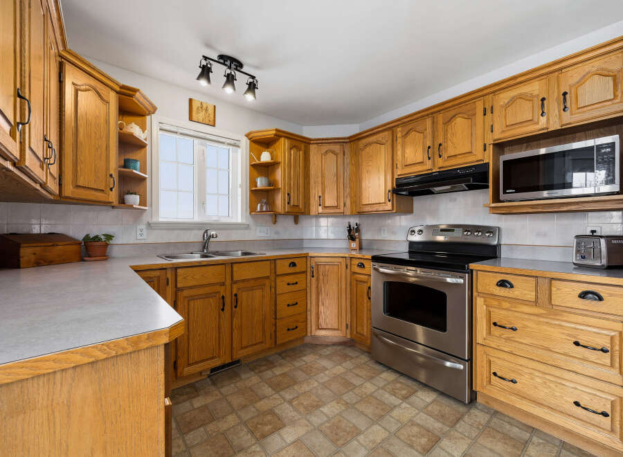 Step into this inviting kitchen, featuring warm wooden cabinetry and ample counter space, perfect for meal preparation and entertaining.