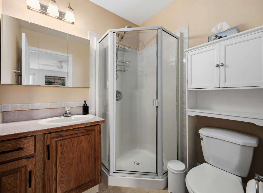 Step into this inviting bathroom featuring a corner shower, a vanity with ample storage, and a convenient toilet.