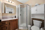 Step into this inviting bathroom featuring a corner shower, a vanity with ample storage, and a convenient toilet.