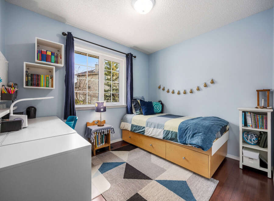 This charming bedroom offers a cozy retreat with its soft blue walls and ample natural light.
