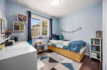 This charming bedroom offers a cozy retreat with its soft blue walls and ample natural light.