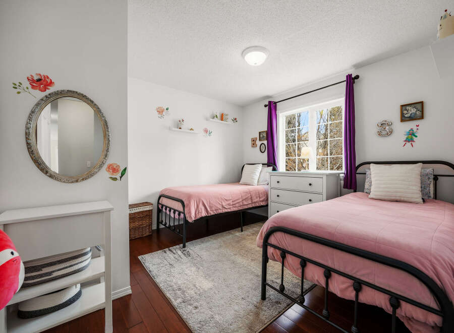 This charming bedroom features two twin beds with pink bedding, perfect for a shared space or guest room.