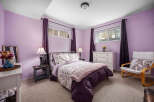 This charming bedroom boasts a serene ambiance with its soft purple walls and cozy carpet flooring.