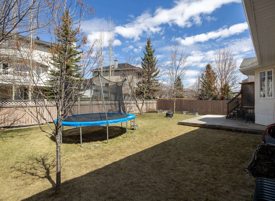 Enjoy outdoor living in this spacious backyard! Featuring a trampoline, a wooden deck, and a lush lawn, this property is perfect for families.