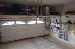This garage offers ample storage space with overhead shelving and wall-mounted bike racks, perfect for organizing tools and equipment.