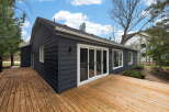 Discover this stunning property featuring a modern exterior with dark siding and a spacious wooden deck, perfect for outdoor entertaining.