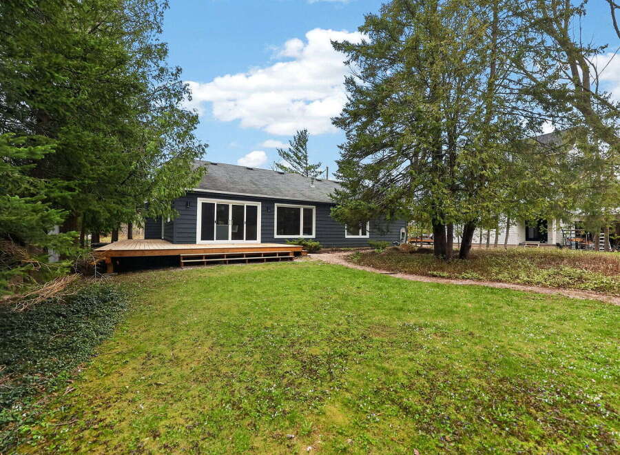 Discover this stunning property featuring a modern, dark-colored exterior and a spacious wooden deck, perfect for outdoor relaxation.