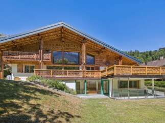 Experience luxury mountain living in this stunning wooden chalet, featuring expansive balconies with intricate carvings and breathtaking views of the surrounding landscape.