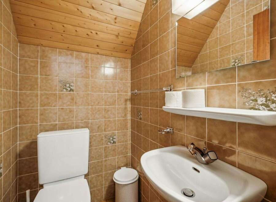 This charming bathroom features a unique design with wooden accents and warm-toned tiles.