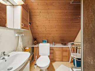 This charming bathroom features a unique sloped ceiling and warm wooden accents, creating a cozy and inviting atmosphere.