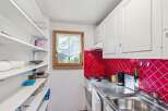 This charming kitchen features a bright red backsplash and ample storage with built-in shelving.