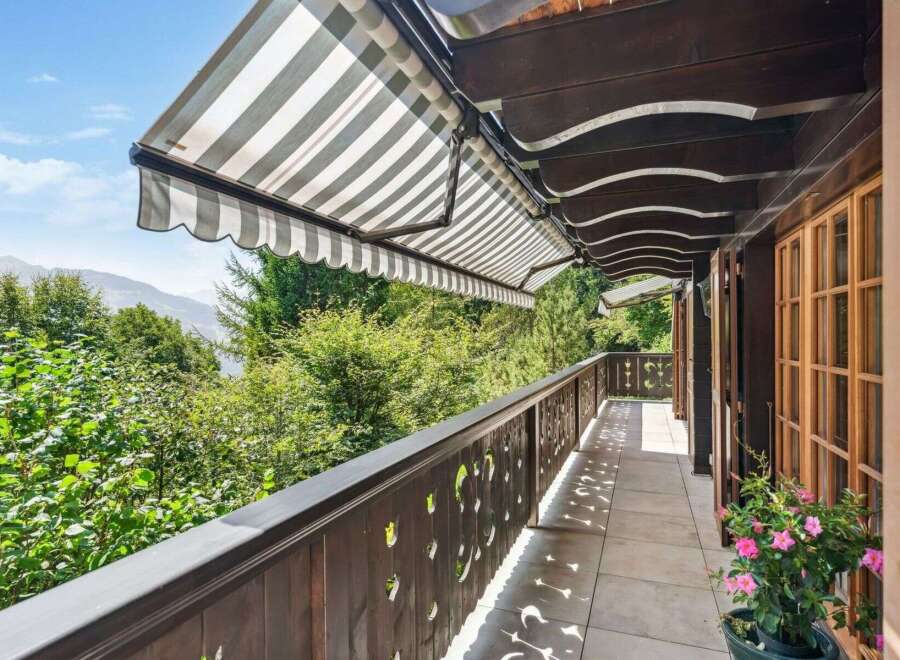 Enjoy breathtaking views from this stunning balcony! This property features a charming wooden balcony with a retractable awning, perfect for relaxing outdoors.