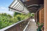 Enjoy breathtaking views from this stunning balcony! This property features a charming wooden balcony with a retractable awning, perfect for relaxing outdoors.