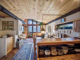 This stunning property boasts a warm and inviting interior with a unique wooden ceiling and exposed beams.