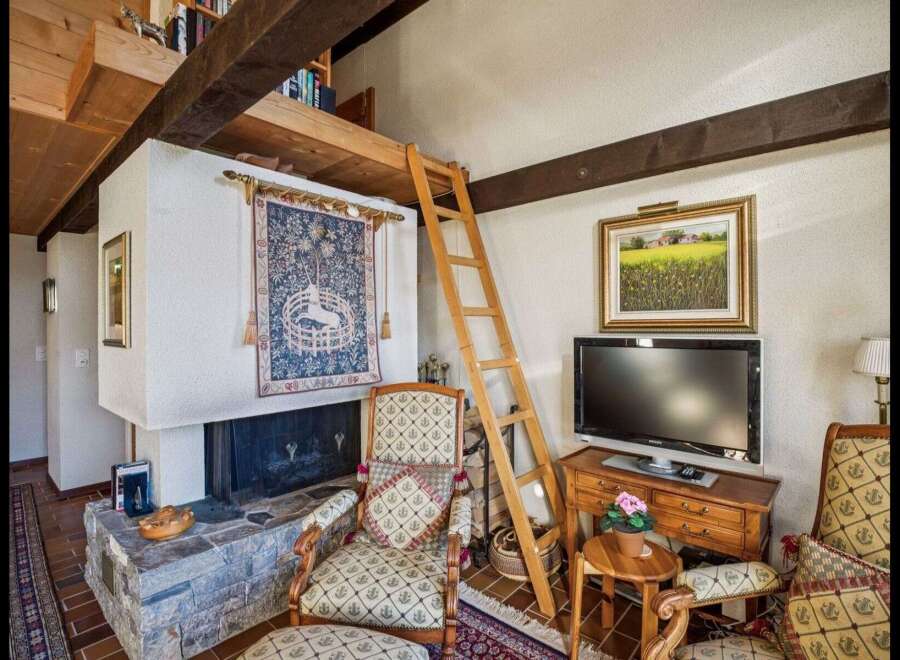 This charming property features a cozy living area with a unique loft space accessible by a wooden ladder.