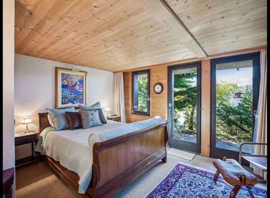 Step into a serene bedroom retreat, where natural light floods through expansive windows, offering breathtaking views of lush greenery.