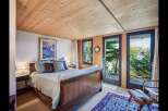 Step into a serene bedroom retreat, where natural light floods through expansive windows, offering breathtaking views of lush greenery.