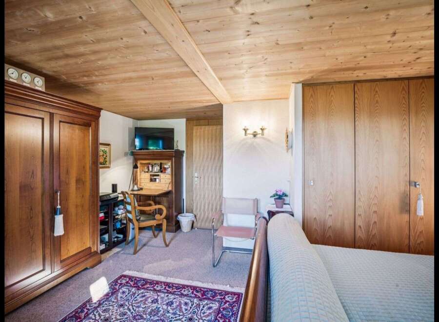 Step into this charming bedroom featuring a warm wooden ceiling and elegant wooden wardrobes.