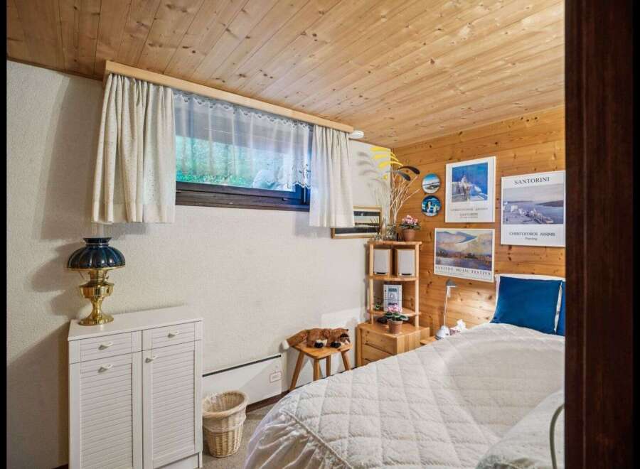 This cozy bedroom features a warm wooden ceiling and walls, creating a rustic and inviting atmosphere.