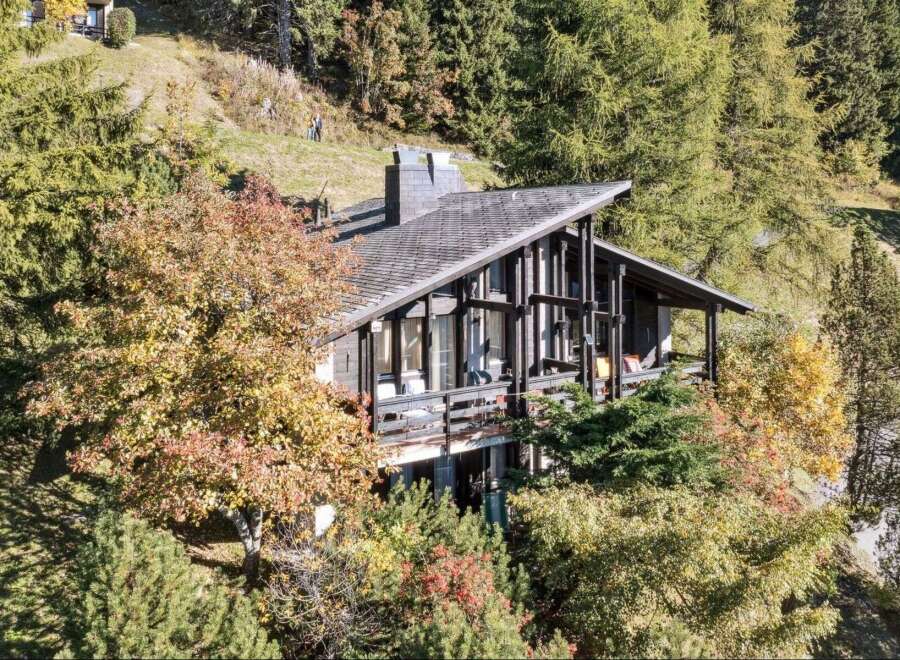Nestled amidst lush greenery, this stunning property boasts a unique architectural design with a distinctive angled roof.