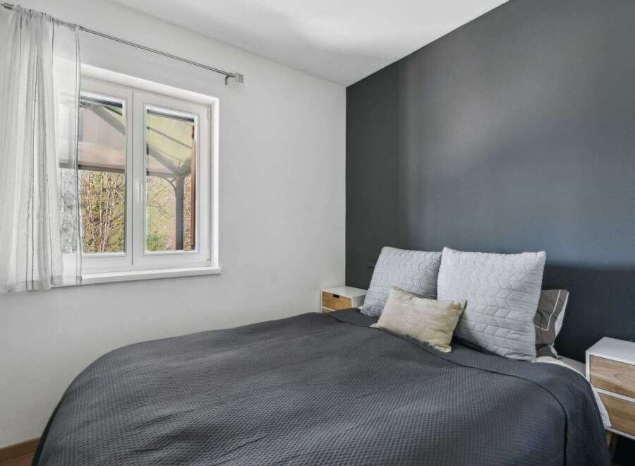 This cozy bedroom offers a serene retreat with its modern design and ample natural light.