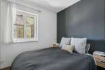 This cozy bedroom offers a serene retreat with its modern design and ample natural light.