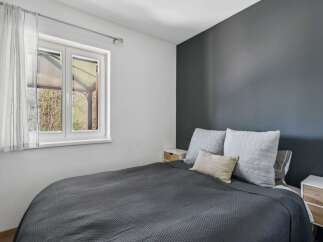 This cozy bedroom offers a serene retreat with its modern design and ample natural light.
