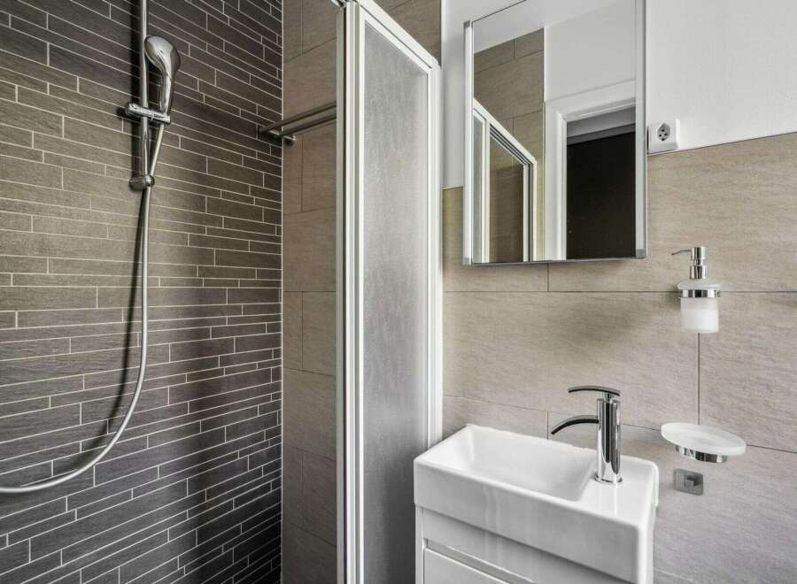 This modern bathroom features a sleek shower with a glass door and stylish tile work.
