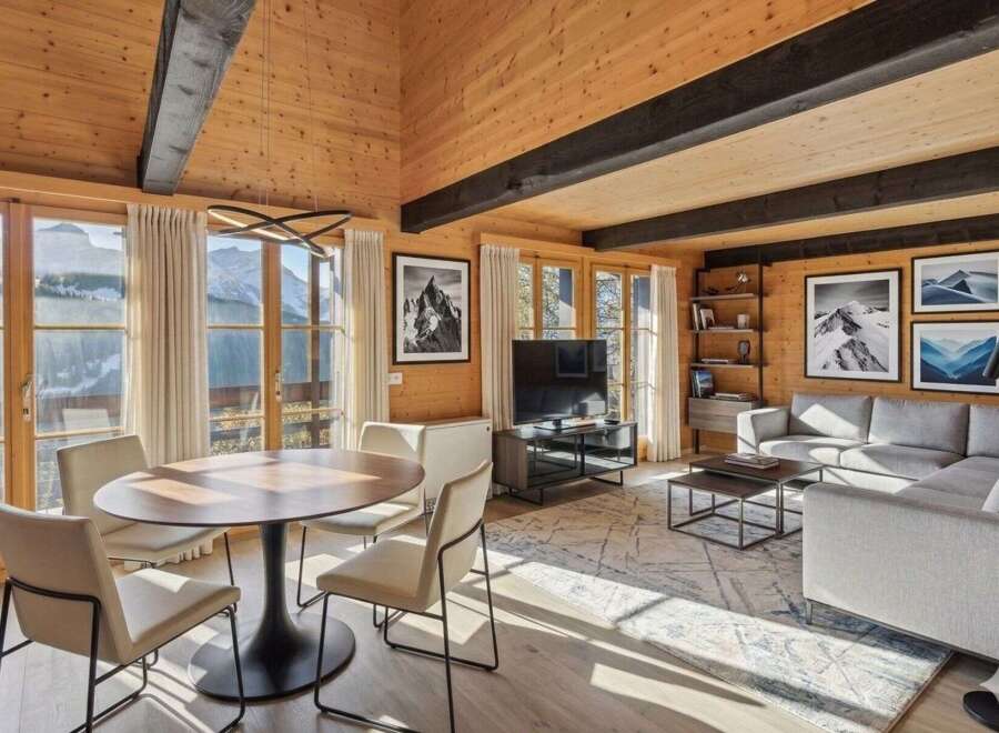 Experience luxury mountain living in this stunning wood-paneled living room, featuring a modern dining set and a spacious sectional sofa.