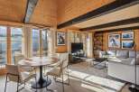 Experience luxury mountain living in this stunning wood-paneled living room, featuring a modern dining set and a spacious sectional sofa.