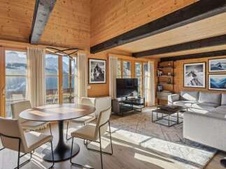 Experience luxury mountain living in this stunning wood-paneled living room, featuring a modern dining set and a spacious sectional sofa.
